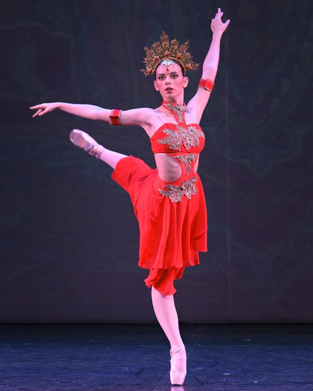 Ballerina in arabesque sulle punte, costume rosso e corona dorata